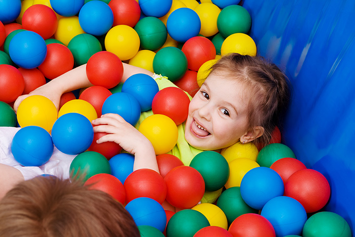 Toddler boy playing with a toy while sitting in a ball pit full of